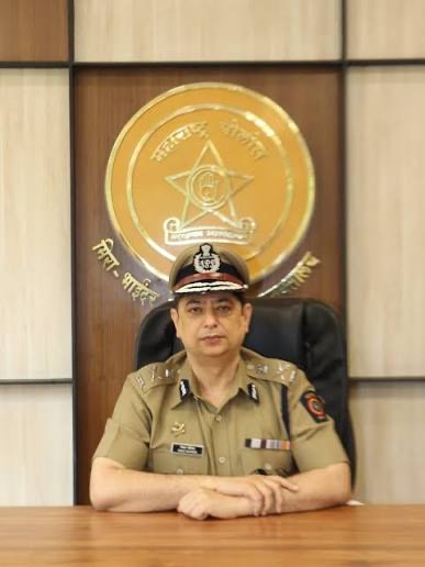 Niket Kaushik, IPS, in full uniform and peaked cap, seated beneath the Maharashtra Police crest at the commissioner's office.