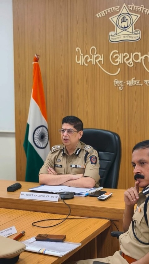 Niket Kaushik chairing a meeting at the Mira-Bhayandar, Vasai-Virar Police Commissionerate, with the national flag and the Maharashtra Police crest behind him and his name plate on the conference table.