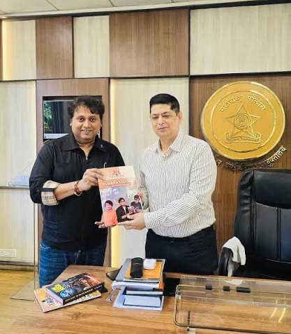 Niket Kaushik receiving a publication in the commissioner's office, the Maharashtra Police crest mounted on the wall behind.