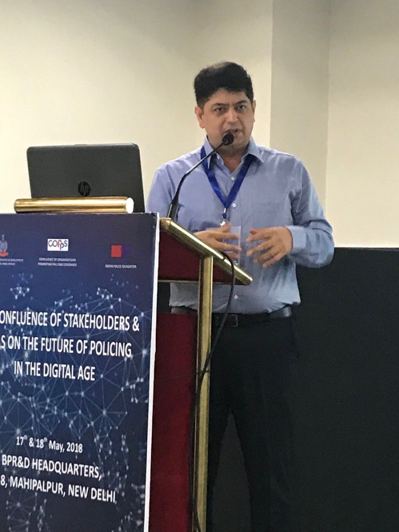 Niket Kaushik speaking from a lectern at the Bureau of Police Research and Development headquarters in New Delhi, beside a banner reading Confluence of Stakeholders on the Future of Policing in the Digital Age, 17 and 18 May 2018.